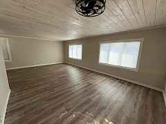 Large living room windows for lots of natural light, whitewashed wood t&g ceilings.